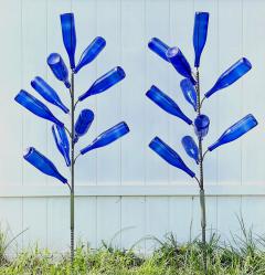 Twin Bottle trees adorned with blue bottles planted in a garden
